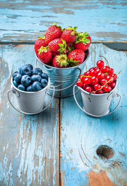 istock Berries in blue tin cans on rustic blue wooden table 1252903301