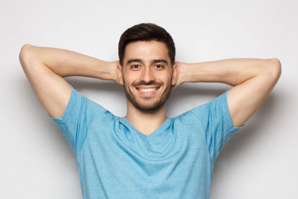 istock Young man standing isolated on gray background with arms behind head, relaxing peacefully in free time 1252905193