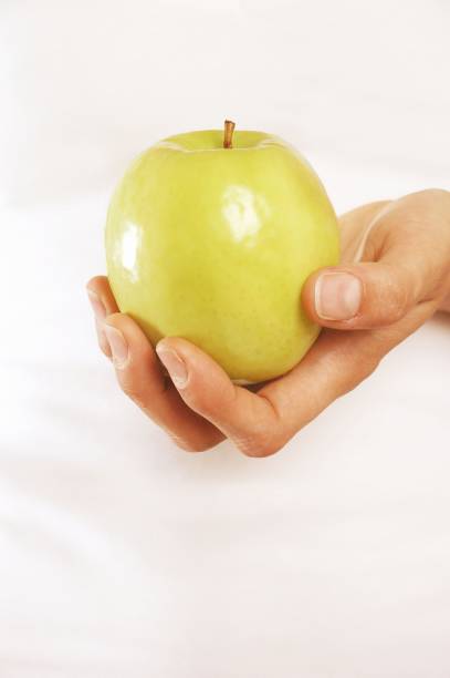 istock Woman holding green apple in hand 1252908371