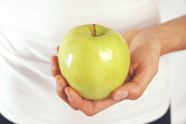 istock Woman holding green apple in hand 1252909094