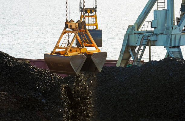 istock Marine loading terminal, trading port. Working port crane and bucket, loading of coal. Grapple crane and pile of hard coal against the sea 1252909153