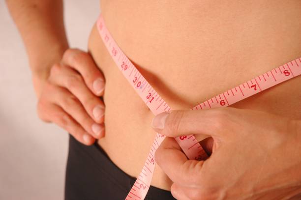 istock Woman measuring waist using tape measure 1252909424