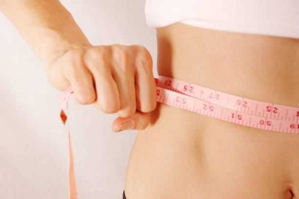 istock Woman measuring waist using tape measure 1252910391
