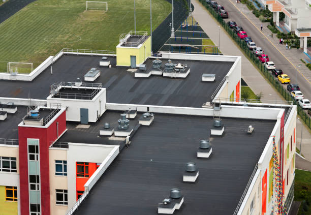Top view dark flat roof with air conditioners and hydro insulation membranes on top of a modern apartment building residential area. stock photo