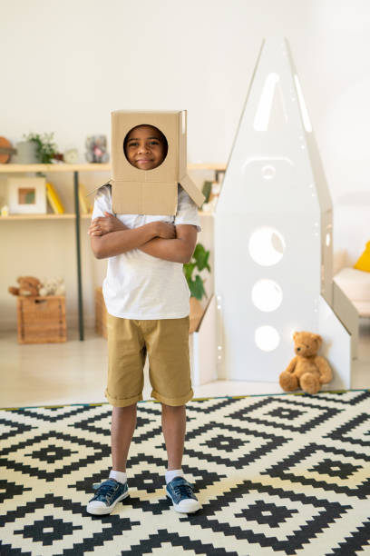 istock Cheerful little boy with cardboard box on his head looking at you through hole 1252919085