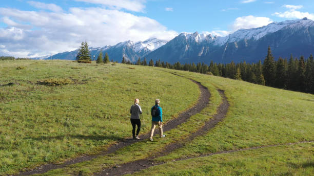 vista aerea di coppie mature che camminano lungo il sentiero di montagna rurale - hiking mature adult women senior adult foto e immagini stock