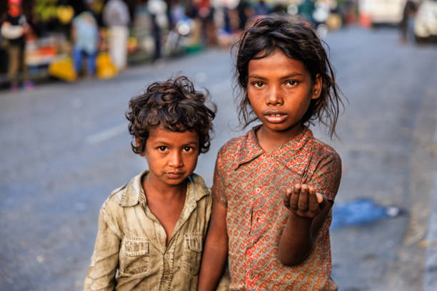 Poor Indian children asking for help Poor Indian children asking for support. Many Indian children suffer from poverty - more than 50% of India's total population lives below the poverty line, and more than 40% of this population are children. poverty stock pictures, royalty-free photos & images