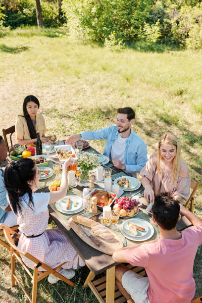 istock Six young friends of various ethnicities gathered by served table for dinner 1252924316