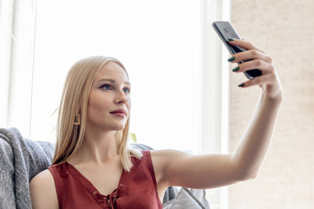 istock young blonde girl takes a selfie while sitting on a sofa 1252926369