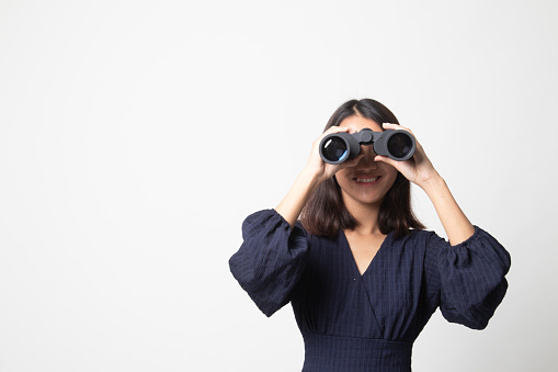 Young Asian woman with binoculars on white background