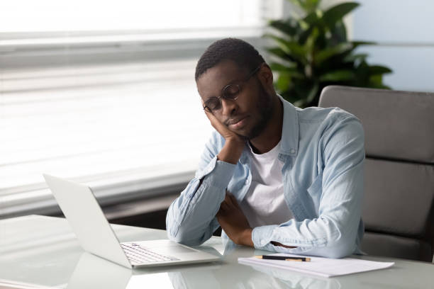 african employee falls asleep seated on chair at workplace - lack of energy imagens e fotografias de stock