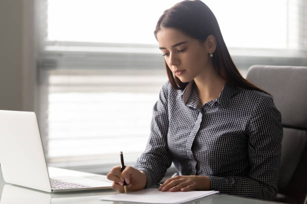 istock Focused female employee sit at workplace writing working with documents 1252926560