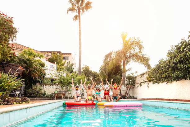 Group happy friends wearing mask making pool party - Young people having fun celebrating event in exclusive swimming pool summer tropical vacation - Friendship and youth holidays lifestyle concept Group happy friends wearing mask making pool party - Young people having fun celebrating event in exclusive swimming pool summer tropical vacation - Friendship and youth holidays lifestyle concept vacation rental mask stock pictures, royalty-free photos & images