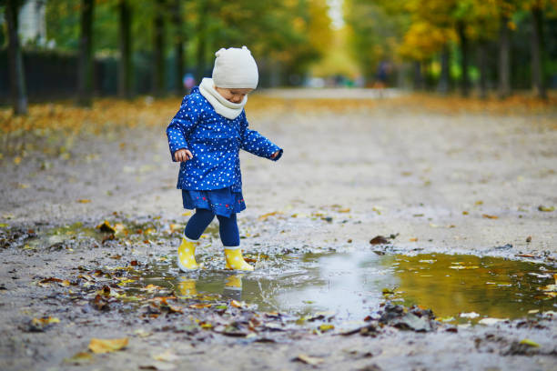 istock Child wearing yellow rain boots and jumping in puddle on a fall day 1252936579