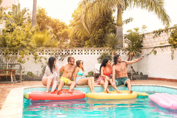 amigos felices haciendo fiesta en la piscina tomando selfie con teléfono inteligente móvil - gente joven milenaria divirtiéndose en exclusivas vacaciones en el complejo tropical - vacaciones de verano y estilo de vida de la gente joven - swimwear bikini swimming pool red fotografías e imágenes de stock