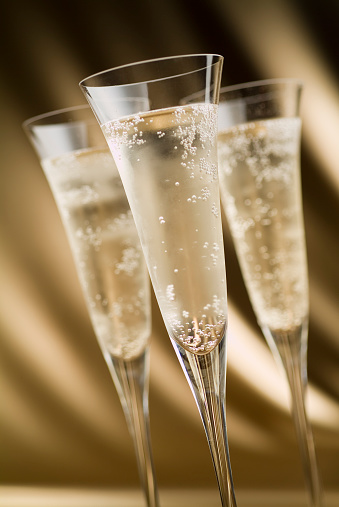 Champagne pouring into a tall glass on the background of bokeh. A popular alcoholic drink.