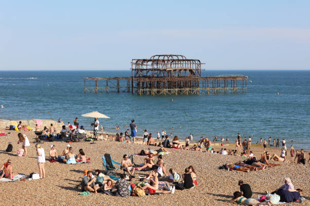 Brighton, England -June 25, 2020: Crowds at Brighton beach amid pandemic. Despite lockdown restrictions due to the Coronavirus, crowds gather on the sandy beach on the hottest day of the year.