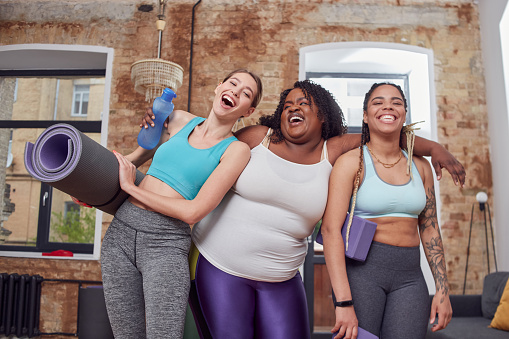 Cheerful afro american woman hugging her friends while laughing together and being prepared for sport lesson