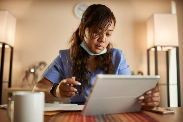istock filipina nurse working from home doing paperwork and using tablet 1252944009