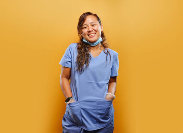 portrait of happy filipina nurse portrait of happy filipina nurse on orange background medical scrubs stock pictures, royalty-free photos & images