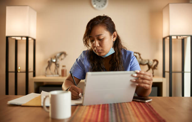 istock filipina nurse working from home doing paperwork and using tablet 1252944127