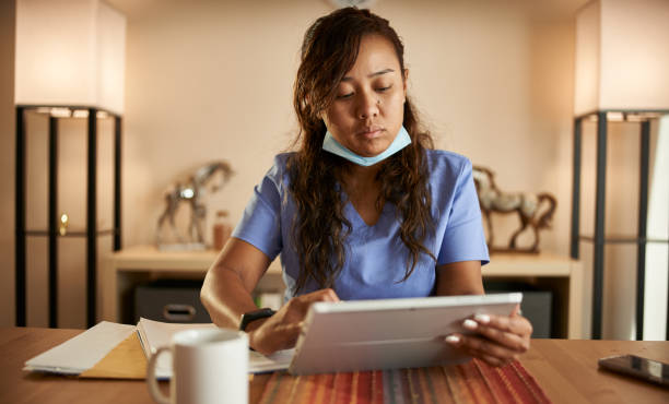 istock filipina nurse working from home doing paperwork and using tablet 1252944155