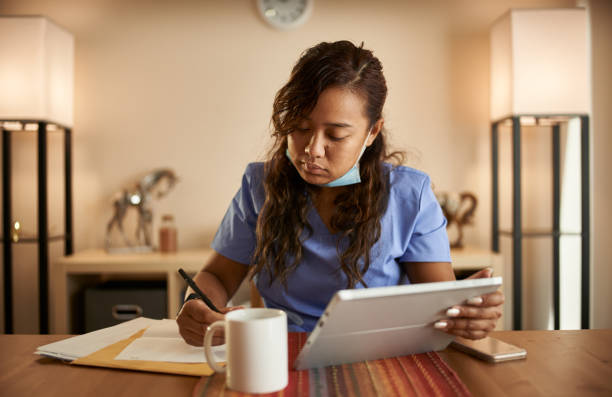 istock filipina nurse working from home doing paperwork and using tablet 1252944156