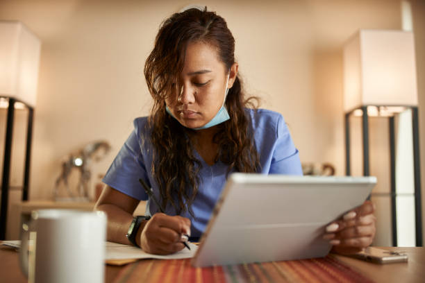 istock filipina nurse working from home doing paperwork and using tablet 1252944184