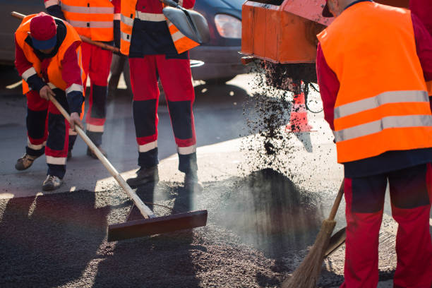 istock Worker leveling fresh asphalt on a road construction site, industrial buildings and teamwork 1252944869