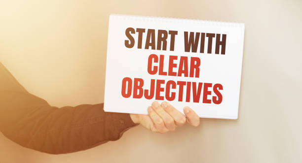 istock Businessman holding a card with text START WITH CLEAR OBJECTIVES. 1252948237