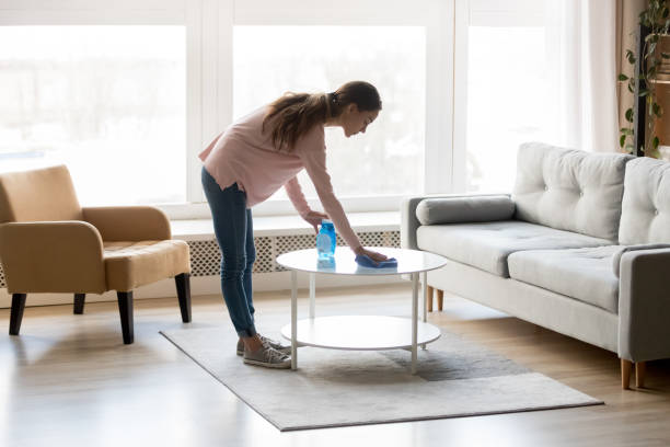 giovane donna di razza mista che pulisce il tavolo con detergente e straccio. - chores wood wet indoors foto e immagini stock