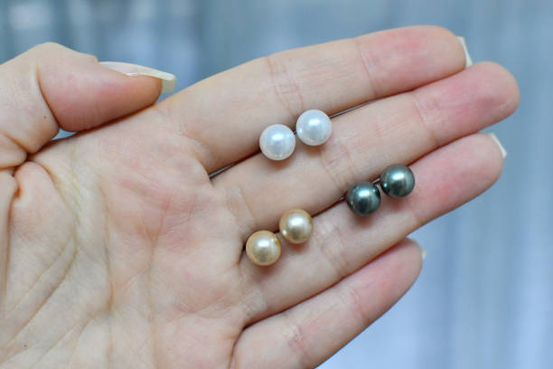블랙, 화이트, 골드 컬러 담수 진주 귀걸이 스터드를 들고 있는 여성 손 - freshwater pearl 뉴스 사진 이미지