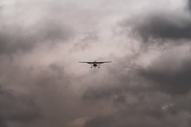 A small light aircraft approaching a runway on a stormy day stock photo