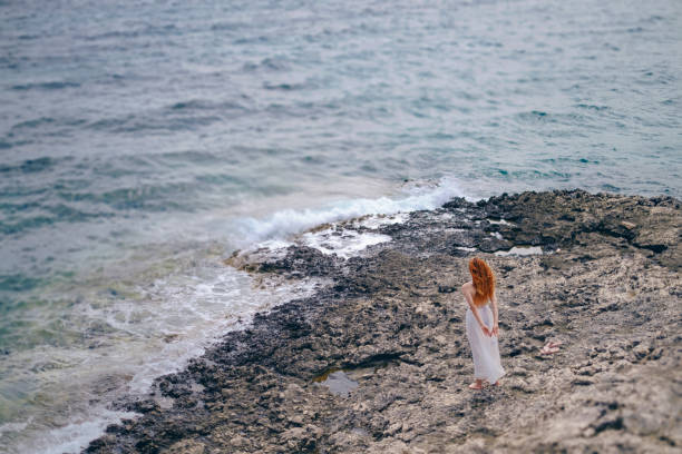 istock Alone Woman Walking on a Rocky Coastal Seaside 1252951797