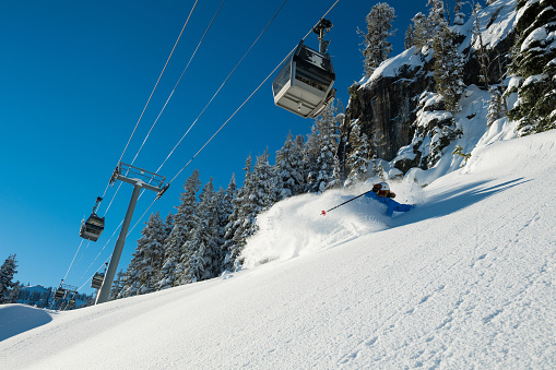 Female skiing fresh powder in the mountains. Winter ski vacation escaping in the mountains. Skiing at Whistler Mountain.