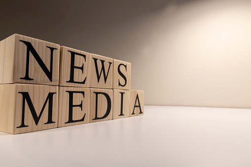 News and media text from wooden cubes. On a white background.