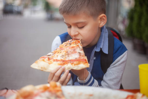 istock one young boy eating a slice of pizzaa. 1252965465