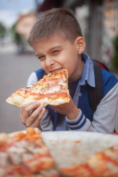 istock one young boy eating a slice of pizzaa. 1252965518