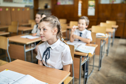 Elementary schoolgirl smiling and looking on the side in the classroom