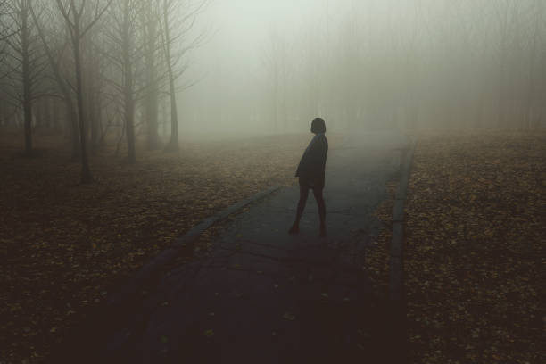 istock Young woman looking behind her back in dark park 1252976213