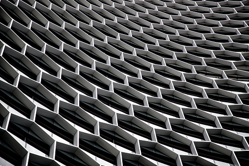 A geometric pattern in the facade of a skyscraper in Singapore. Hexagonal honey comb design to create a different atmosphere in this office building. Corporative and modern architecture which fits with a Asian metropolis as Singapore