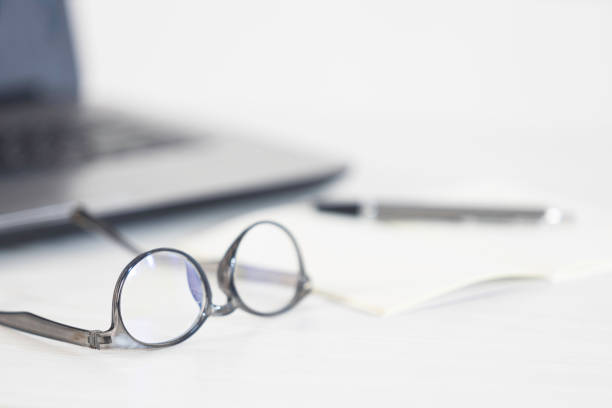 istock Eyeglasses, open notebook, pen and laptop on the office table. 1252977949