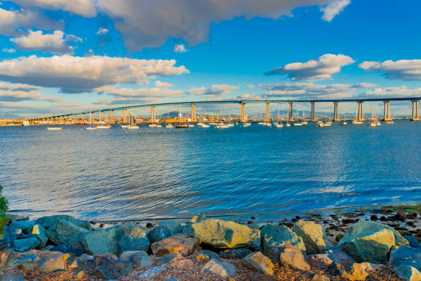 мост коронадо бэй в сан-диего с лодками и светящейся водой - coronado bay bridge стоковые фото и изображения