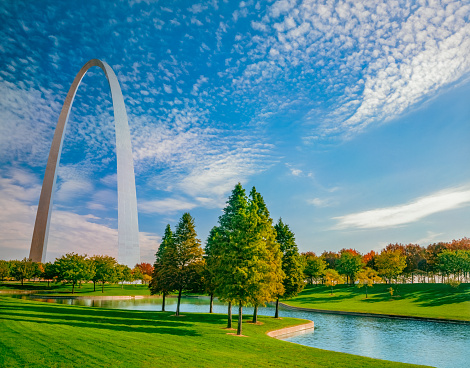 Grass, water and autumn trees surround the Gateway Arch in Saint Louis, Missouri. This is all in the Gateway Arch National Park.