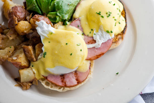 istock Eggs Benedict. Poached eggs w/ potato hash served in a cast iron skillet. English muffin. eggs, country ham, melted cheese, & homemade hollandaise sauce. Classic French or American cuisine favorite. 1252991498