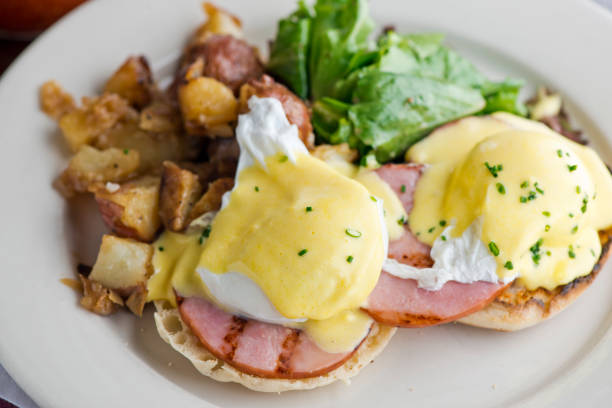 istock Eggs Benedict. Poached eggs w/ potato hash served in a cast iron skillet. English muffin. eggs, country ham, melted cheese, & homemade hollandaise sauce. Classic French or American cuisine favorite. 1252991502