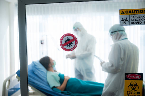istock virus control experts doctor in PPE suit working for disease treatment with coronavirus COVID-19 infected patient people in hospital quarantine negative pressure room, outbreak alert sign 1252993446
