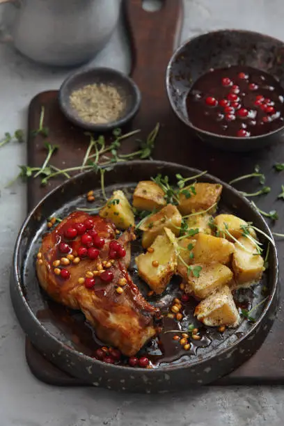 Photo of Scandinavian Food. Pork Chops with Wild Lingonberry Sauce and Baked Potato Wedges with Herbs