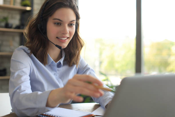 istock Freelance operator talking with headsets and consulting clients from home office. 1253011949