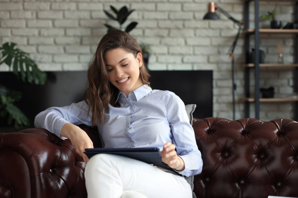 istock Young smiling woman with tablet pc on the sofa. 1253012764
